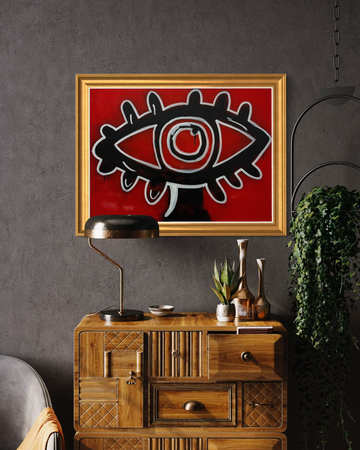 Adivino Gallery original red eye artwork displayed in a gold frame above a wooden console